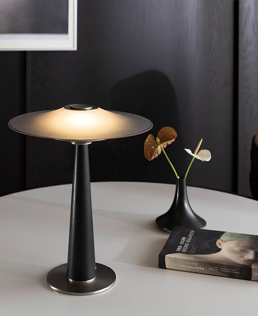 Bedroom table lamp lit on a round table beside a small flower vase