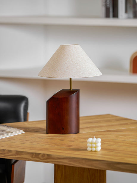 Bedroom table lamp lit on a wooden desk near open shelving