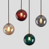 Four glass spheres in red, amber, smoke and green on a plain gray field