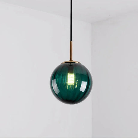 Deep green glass sphere with a brass holder and a lit bulb inside