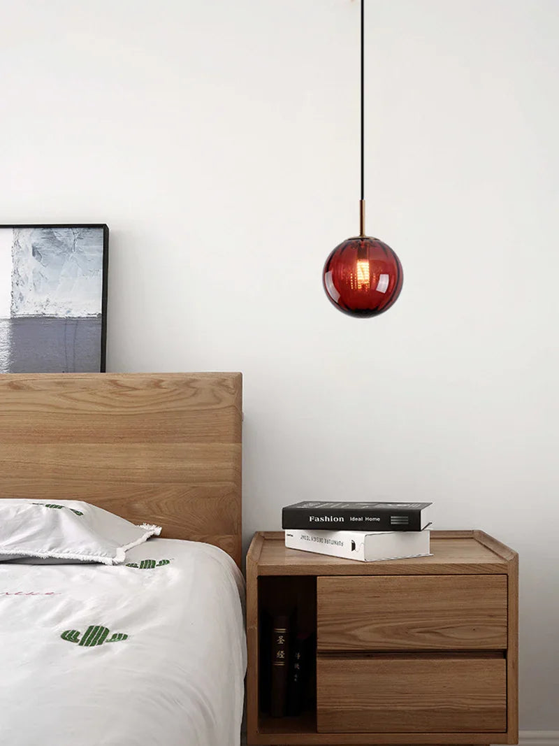 Red sphere hanging over a nightstand with books beside a made bed