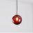 Red glass sphere with a brass holder and a lit filament bulb inside