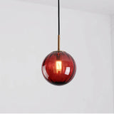Red glass sphere with a brass holder and a lit filament bulb inside