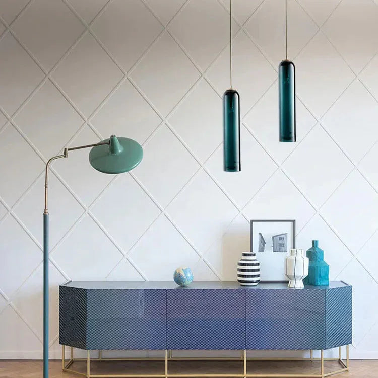 Two slim glass tube pendants lit above a dark blue sideboard