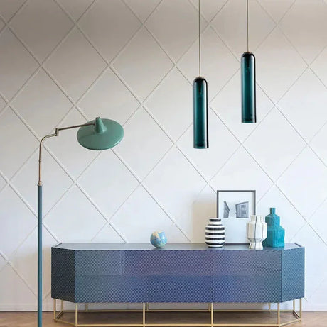Two slim glass tube pendants lit above a dark blue sideboard
