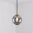 Smoke gray glass sphere with a brass holder and a lit bulb inside