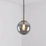 Smoke gray glass sphere with a brass holder and a lit bulb inside
