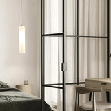 A white tube pendant lit in a corner beside a window frame