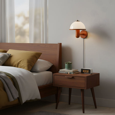 Oak wall lamp lit over a wood nightstand in a plain bedroom at night