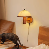 Oak wall lamp lit warm beside a bed with a leather headboard