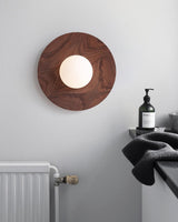 Lamp lit on a bathroom wall above a radiator with a towel and a bottle
