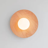 Oak disc lit warm, the frosted globe glowing at the middle of the grain