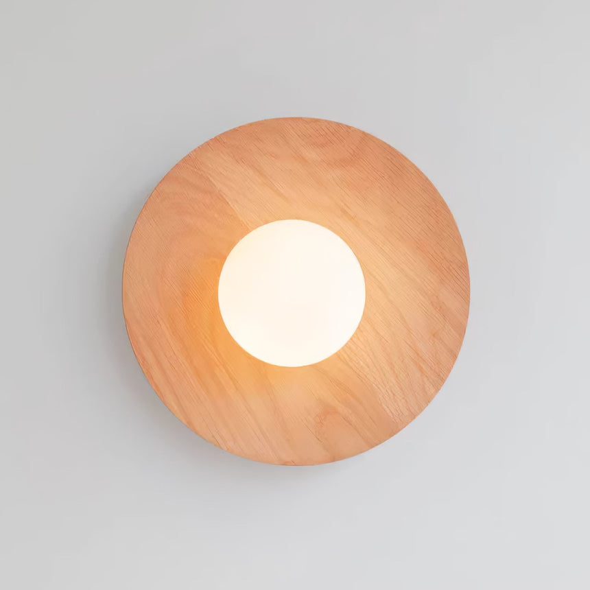 Oak disc lit warm, the frosted globe glowing at the middle of the grain