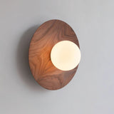 Black walnut disc lit warm with the frosted globe glowing off center