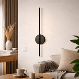 Lit above a sofa with a linen cushion, a side table, a mug and a tall vase