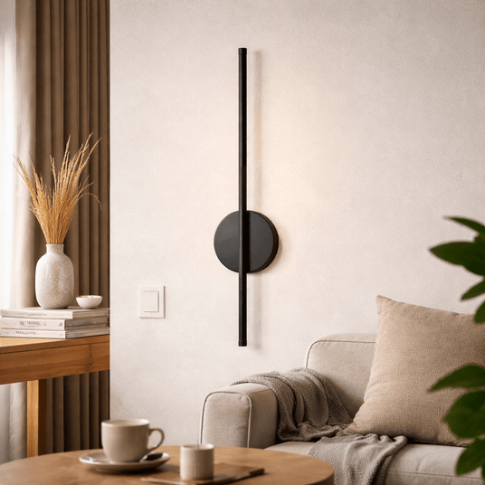 Lit above a sofa with a linen cushion, a side table, a mug and a tall vase