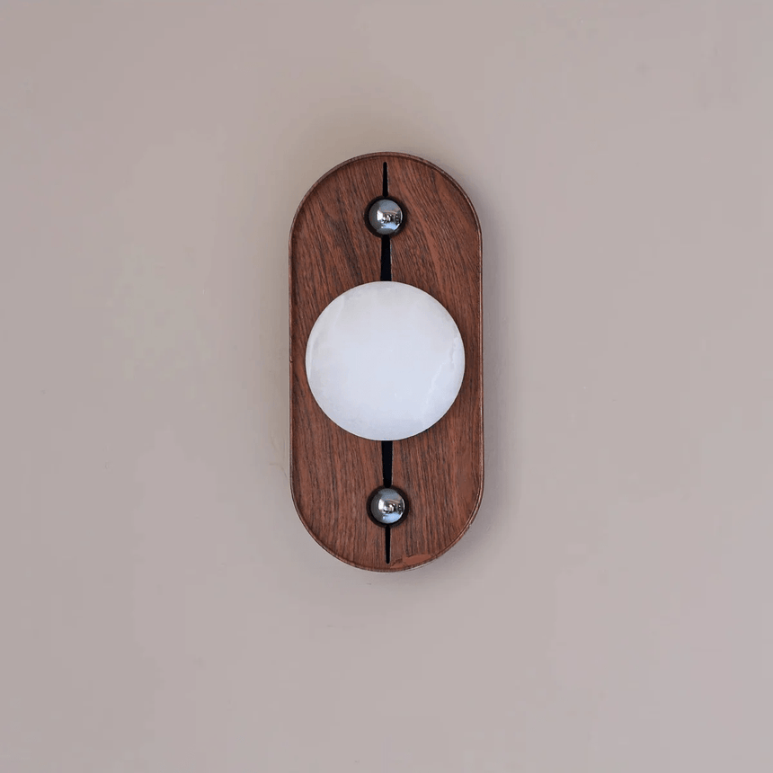 Alabaster orb lit cool white on an upright oval walnut plate