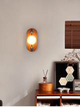 Alabaster sconce lit on a wall beside a cabinet and a small mirror