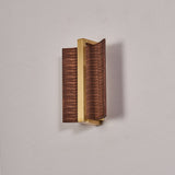 The dark wood version with a brass center bar, unlit against a gray wall