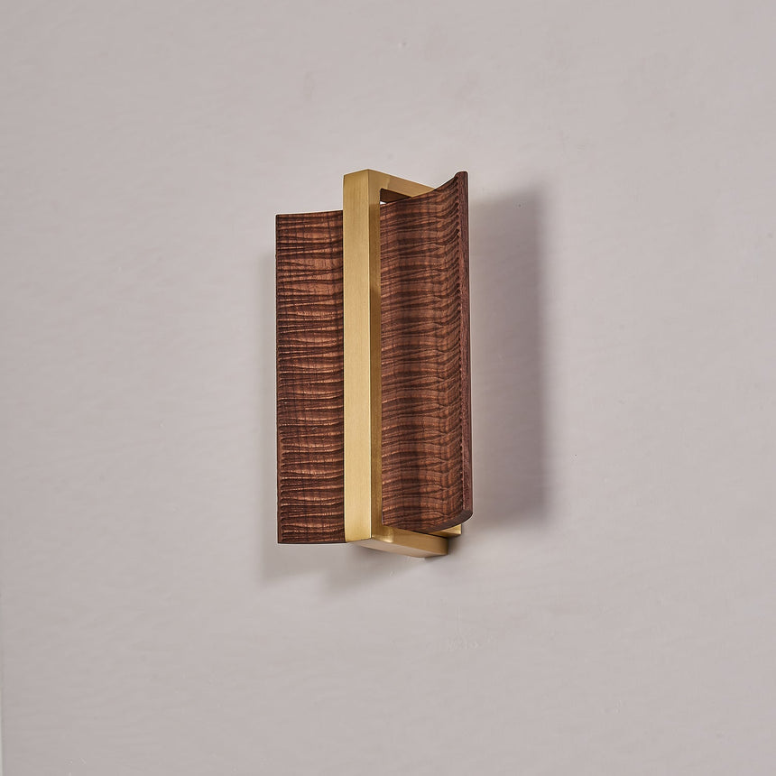 The dark wood version with a brass center bar, unlit against a gray wall