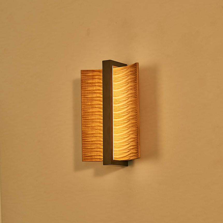 The pale wood version lit against a warm ochre wall, glowing at the slot