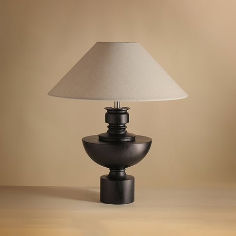 Beige table lamp with the black turned vase base against a plain ground
