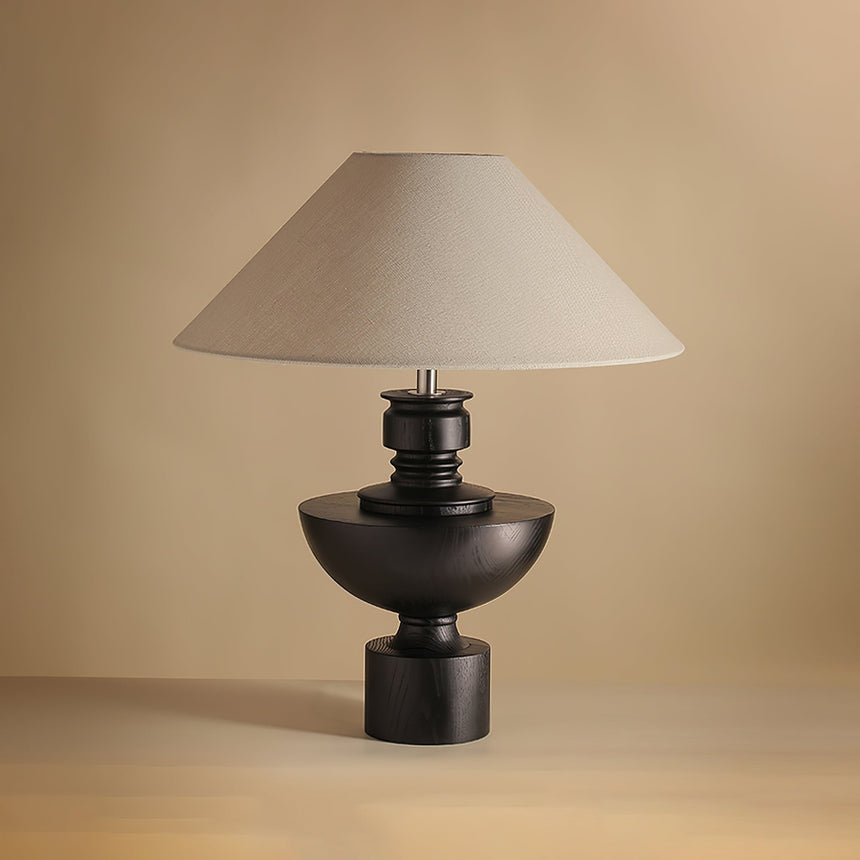 Beige table lamp with the black turned vase base against a plain ground