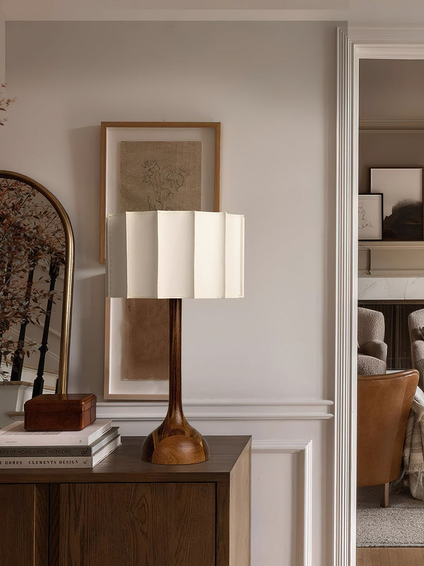 Beige table lamp lit on a console in a pale hallway