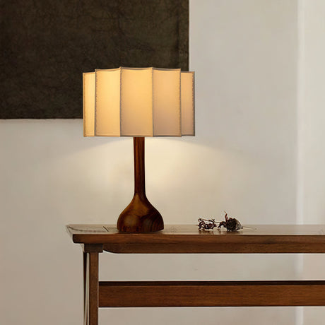 Beige table lamp lit on a narrow console table by a wall