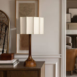 Beige table lamp lit on a console beside books and a box