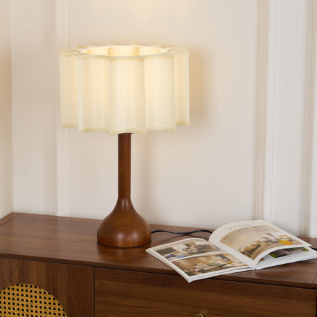 Beige table lamp lit on a walnut sideboard beside an open book
