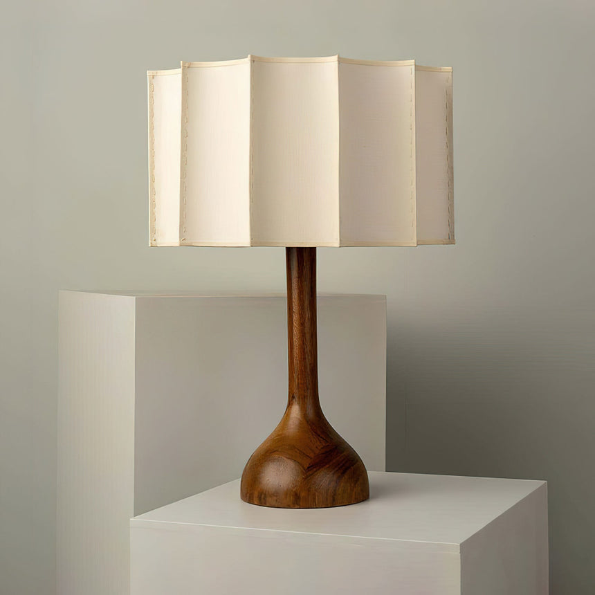 Beige table lamp unlit on a white plinth, the trumpet foot visible