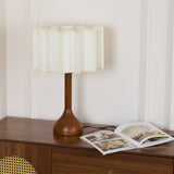 Beige table lamp unlit on a sideboard beside an open magazine