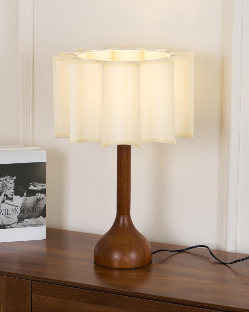 Beige table lamp lit on a sideboard beside a framed photograph