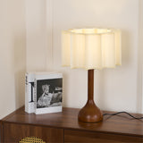 Beige table lamp lit on a sideboard beside two standing books