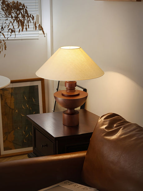 Beige table lamp lit on a cabinet beside a window and a leather chair