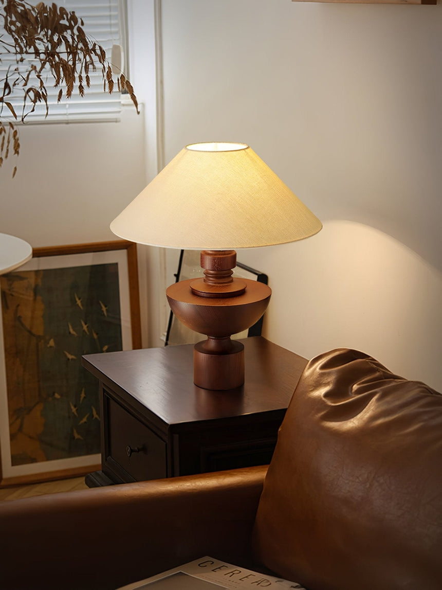 Beige table lamp lit on a cabinet beside a window and a leather chair