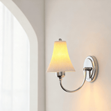 The sconce lit on a wall beside an arched doorway