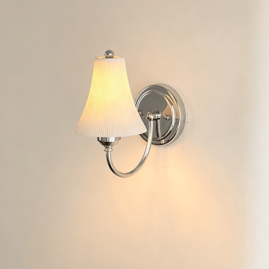 The ribbed bell shade glowing on a cream wall, the chrome plate behind