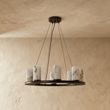 The same black ring with its eight stone cylinders unlit on a plaster wall