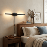 Black bar lit above a bed with layered pillows and a bedside table with books