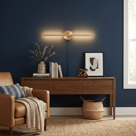 Gold bar lit on a deep blue wall above a desk with framed prints and a basket