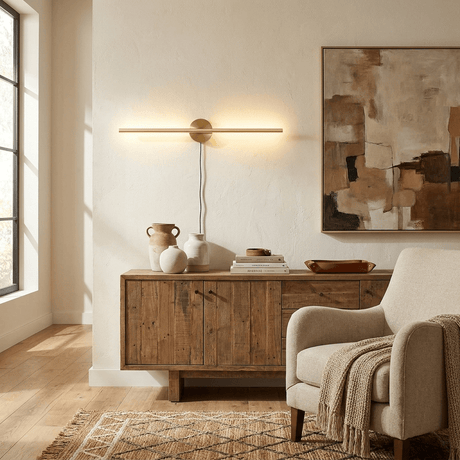 Gold bar lit above a wood cabinet with a bowl and a vase in a sunlit room