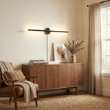 Black bar lit above a walnut sideboard with a framed print and dried stems