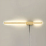 The slim gold profile lit, a narrow band of light across a pale wall