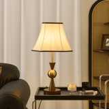 Walnut version of the lamp with a cream shade lit on a metal trolley