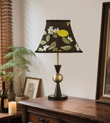 Embroidered shade table lamp lit on a dark wooden console beside a mirror
