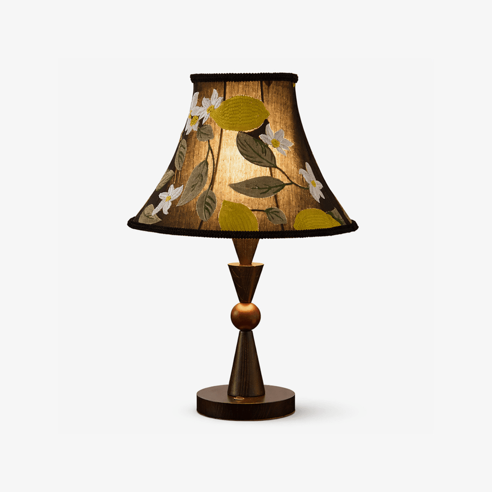 Black table lamp with an embroidered shade on a turned wood stem, plain background