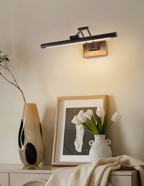 Black bar lit over a framed print, a ribbed vase and white tulips on a console