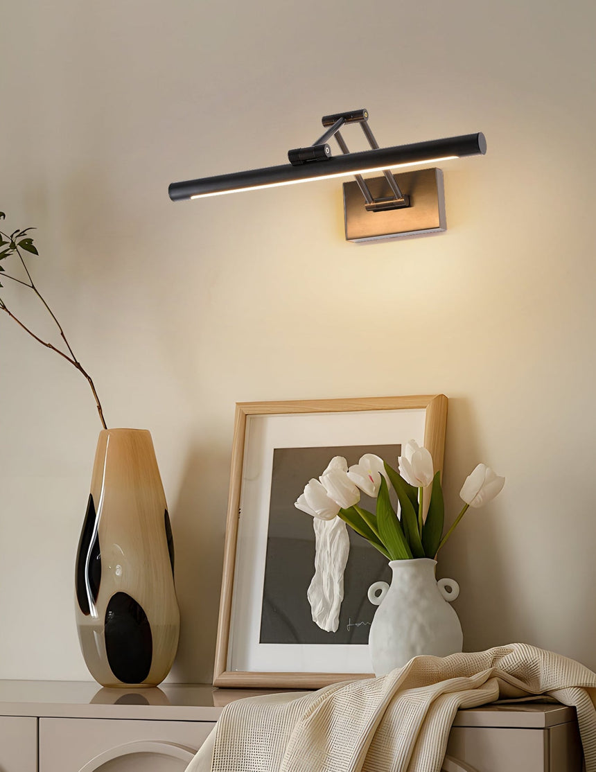 Black bar lit over a framed print, a ribbed vase and white tulips on a console